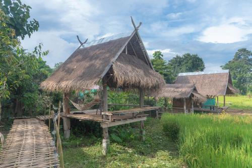 a hut with a thatched roof in a field at Paddy Fields Haven - Natures Nest in Pai