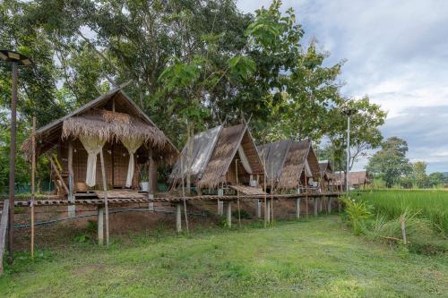 a row of huts in a field with grass at Paddy Fields Haven - Natures Nest in Pai