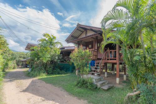 a house with a staircase next to a dirt road at Paddy Fields Haven - Natures Nest in Pai