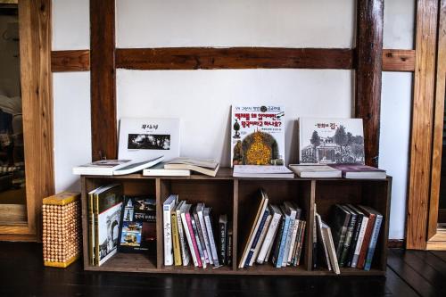 a book shelf filled with books next to a wall at Bonghwangjae Hanok Guesthouse in Gongju