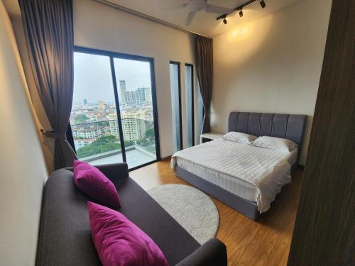 a bedroom with a bed and a couch and a window at Beacon Executive Suites - Penang in George Town