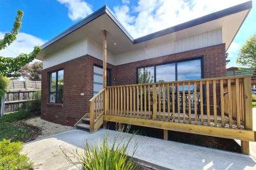 a home with a large deck in front of it at Cedar Cottages Blackmans Bay in Kingston