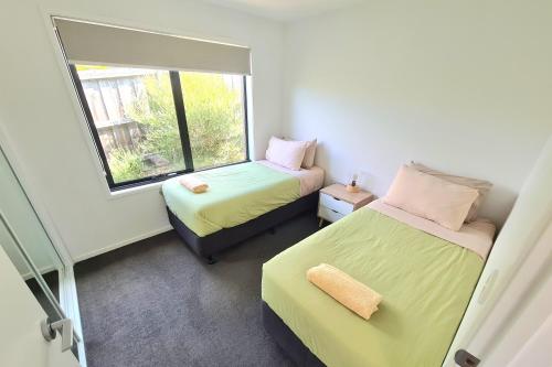 two beds in a small room with a window at Cedar Cottages Blackmans Bay in Kingston