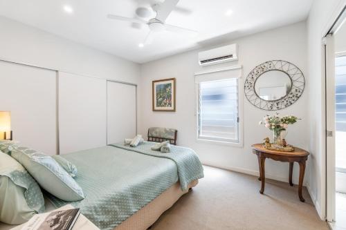 布里斯班On Esplanade own flat & Pool, Manly cafe precinct的卧室里有一张床、一面镜子和一张桌子