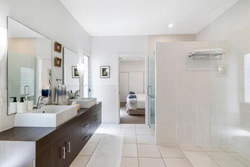 ein weißes Bad mit einem Waschbecken und einer Dusche in der Unterkunft On Esplanade own flat & Pool, Manly cafe precinct in Brisbane