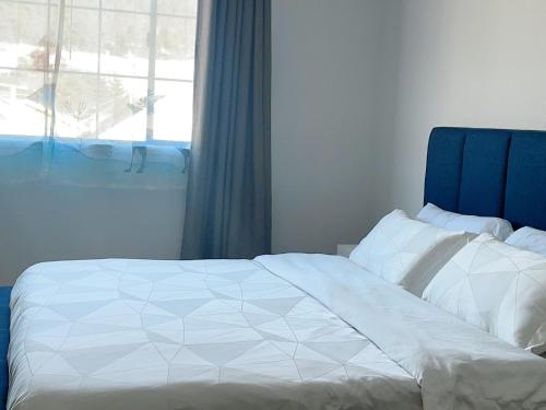 a bedroom with a bed with a blue headboard and a window at 靠近舊金山國際機場的民宿 in Daly City