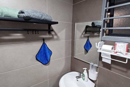 a bathroom with a sink and a toilet with blue towels at Homestay ARC Cozyhome Austin Hills 4-5pax in Johor Bahru