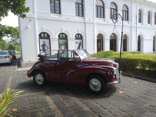an old red car parked in front of a building at Mini's Residence in Colombo