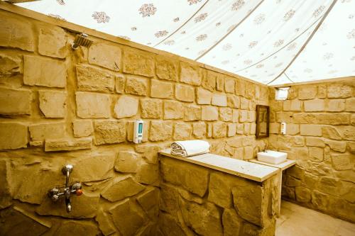 a stone walled bathroom with a sink and a phone at Tripli Hotels Stay Inn Resort Jaisalmer in Sām
