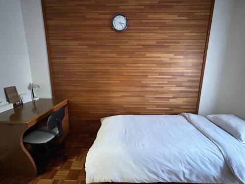 a bedroom with a bed and a clock on a wall at KIX House Waraku III 和楽三号館 in Izumi-Sano