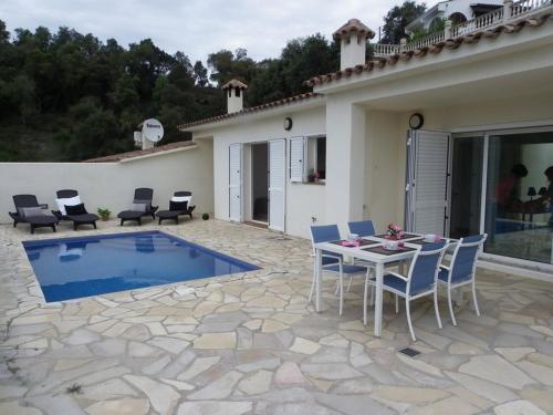 un patio con mesa, sillas y piscina en DANLUX MOLI 13, en Tossa de Mar
