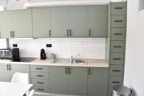 a kitchen with white cabinets and a sink at Polles Εlies Cozy Αpartment in Aegina Town