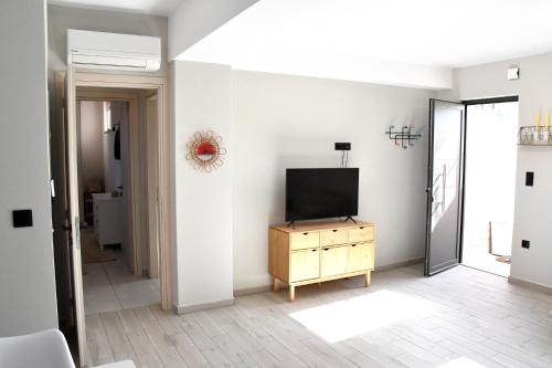 a living room with a television on a wooden dresser at Polles Εlies Cozy Αpartment in Aegina Town