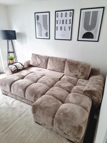 a large couch in a living room with pictures on the wall at 2 Bed Cosy Aylesbury House with Parking in Buckinghamshire