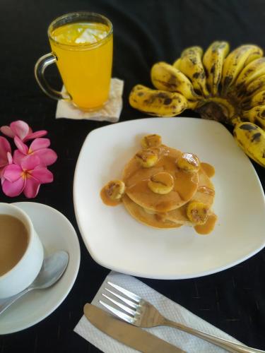 a plate of pancakes with a cup of coffee and bananas at Kuta Garden in Kuta Lombok