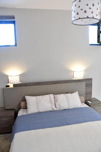 a bedroom with a bed with two lamps on top at Polles Εlies Cozy Αpartment in Aegina Town
