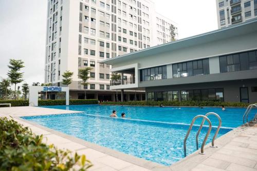 uma piscina em frente a um edifício com pessoas nele em Căn hộ 53m đủ nội thất 1PN 1WC bếp free hồ bơi, GYM, BBQ tại Warterpoint Bến Lức em Bến Lức