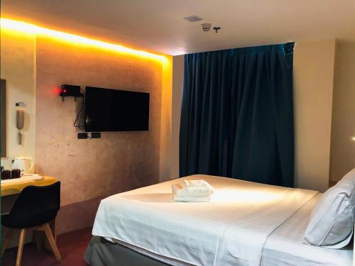 a hotel room with a bed and a tv on the wall at Sempre Premier Inn - MACTAN AIRPORT HOTEL in Mactan
