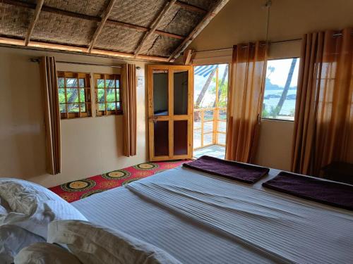 ein Schlafzimmer mit einem großen Bett in einem Zimmer mit Fenstern in der Unterkunft Cola Beach Sunset Bay in Cola