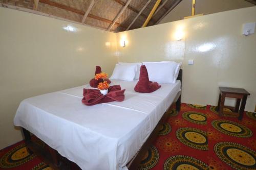 a bedroom with a white bed with flowers on it at Cola Beach Sunset Bay in Cola