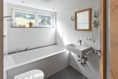 a white bathroom with a tub and a sink at Alpenhaus Montafon by Pferd auf Wolke in Gargellen