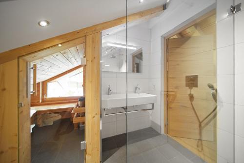a bathroom with a sink and a glass shower at Alpenhaus Montafon by Pferd auf Wolke in Gargellen