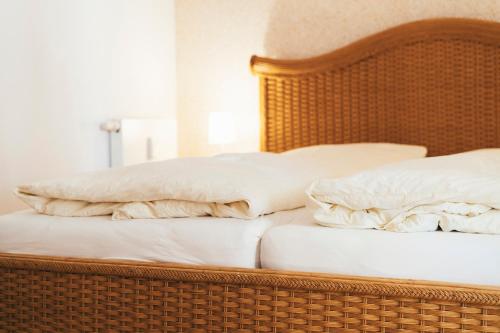 uma cama de vime com duas almofadas em cima em Haus Sonnenhaken Wohnung 1 em Norderney