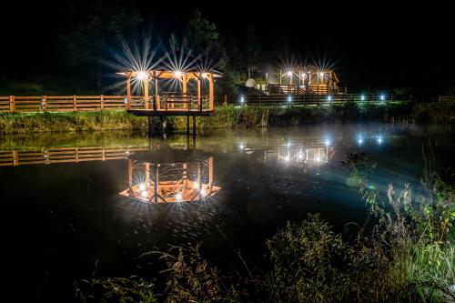 a bridge in the water at night with lights at Glamping Pod Gwiazdami Pietrusza Wola in Pietrusza Wola