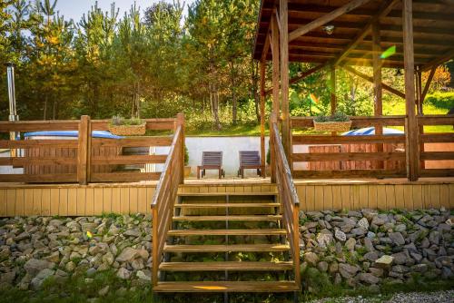 a wooden staircase leading to a deck with two chairs at Glamping Pod Gwiazdami Pietrusza Wola in Pietrusza Wola