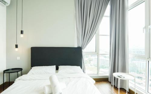 a bedroom with a bed with a black headboard and windows at Boulevard Service Apartment KL by Airhost in Kuala Lumpur
