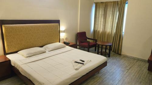 a hotel room with a bed and a chair at The Golden Park in Madurai