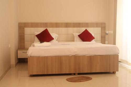 a bedroom with a large bed with red pillows at Sridham Holiday Vrindavan in Vrindāvan