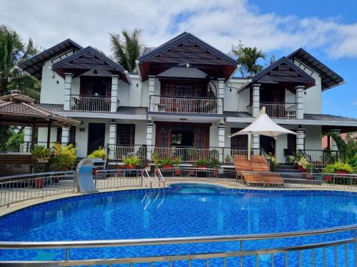a hotel with a swimming pool in front of a building at Sriniketana Homestay in Madikeri