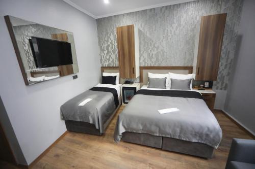 a hotel room with two beds and a flat screen tv at Yuvam akmarmara hotel in Istanbul
