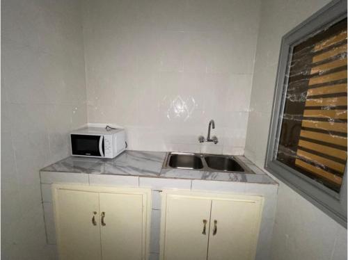 una pequeña cocina con fregadero y microondas en Residence in Tounkaranke, en Bamako