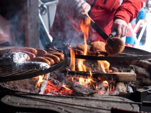 a person cooking sausages and sausage on a grill at Break Sokos Hotel Koli Kylä in Kolinkylä