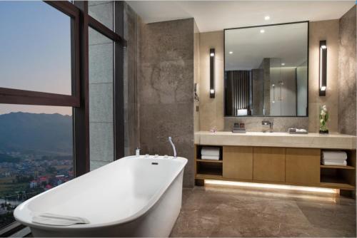 een badkamer met een bad, een wastafel en een spiegel bij Wanda Jin Pingxiang in Pingxiang