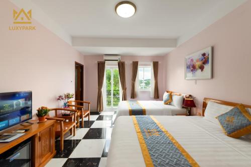 Luxy Park Hotel & Residences - Phu Quoc City Centre في فو كووك: غرفة فندقية بسريرين وتلفزيون
