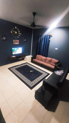 uma sala de estar com um sofá e um relógio na parede em Alysha Homestay em Kuala Lipis