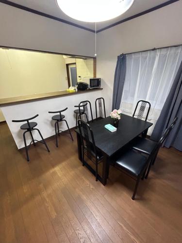 a dining room with a black table and chairs at 高島市一棟貸切 貸別荘グループファミリーok 大人数でご利用だとお得連泊がお得 in Takashima