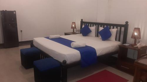 a bedroom with a large bed with blue pillows at Alnaro Hotel & Resort in Moratuwa