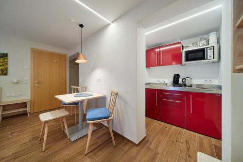 a kitchen with red cabinets and a table and chairs at Alpenhaus Montafon by Pferd auf Wolke in Gargellen