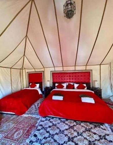 a bedroom with two red beds in a tent at Sunset Camp Merzouga in Merzouga