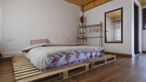 ein Schlafzimmer mit einem Bett auf einer hölzernen Plattform in der Unterkunft Kanatal Kutir in Kanatal