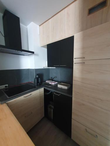 uma pequena cozinha com electrodomésticos pretos e armários de madeira em Le Cosy - Queen-size, full équipé, wifi, parking em Namur