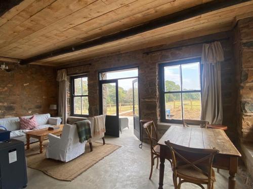 sala de estar con mesa y sofá en Yellowwoods Farm - WILLOUGHBYS COTTAGE and OLD STABLES COTTAGE, en Curryʼs Post