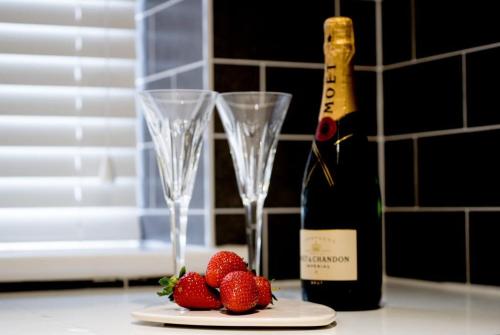 Bucklesham的住宿－Purdis Farm - Flat 4，2杯香槟酒和草莓,旁边是1瓶香槟