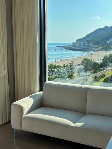 a couch in front of a window with a view of the beach at Paul Mare Pool Villa in Busan