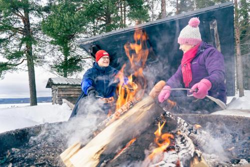 two people standing around a fire in the snow at Break Sokos Hotel Bomba in Nurmes