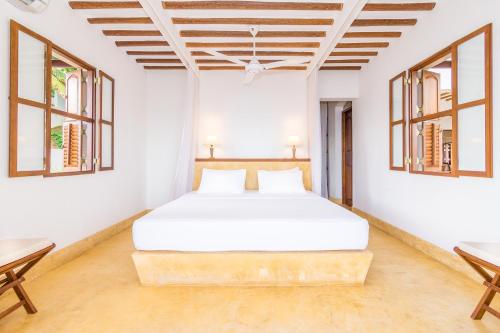 a bedroom with a white bed and two windows at Cinnamon House by The Serendipity Collection in Weligama